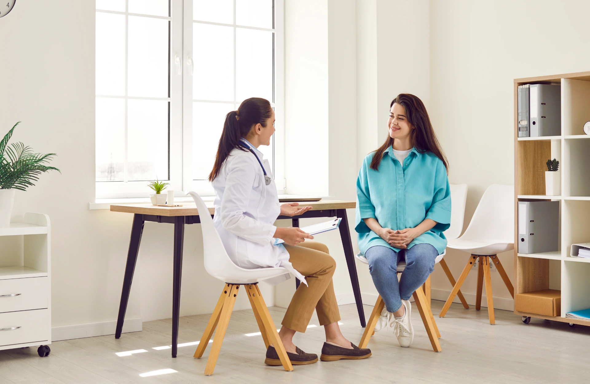 Doctor consulting with smiling female patient in a bright, modern medical office